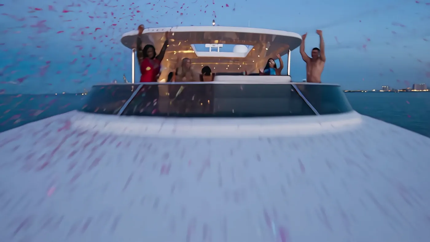 Low and fast over the bow toward the upper deck, confetti streaking past, guests with arms in the air.