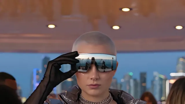 Closer on NOVA, a gloved hand lifting mirrored visor glasses.