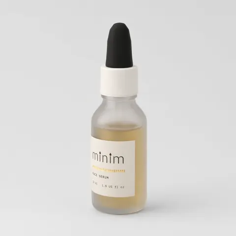 Packshot of a frosted glass serum bottle with a white collar and black dropper bulb, label reading minim, on a light grey ground.