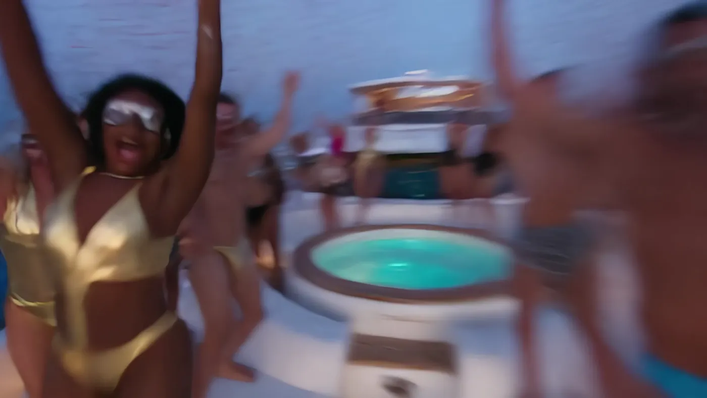 A fast first-person pass: dancers in gold with arms raised, the jacuzzi blurred in the corner.